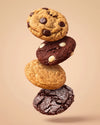 Four floating chocolate chip cookies of varying styles stacked vertically against a solid beige background.
